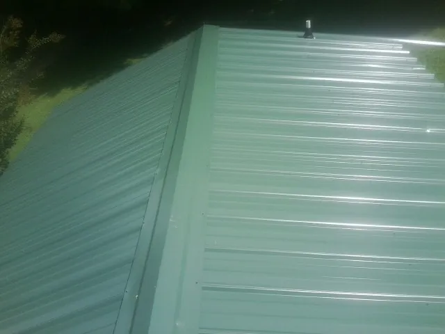 New green metal panels meeting at the ridge of a roof in Hooper